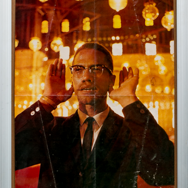 Amber toned photograph of Malcom X praying